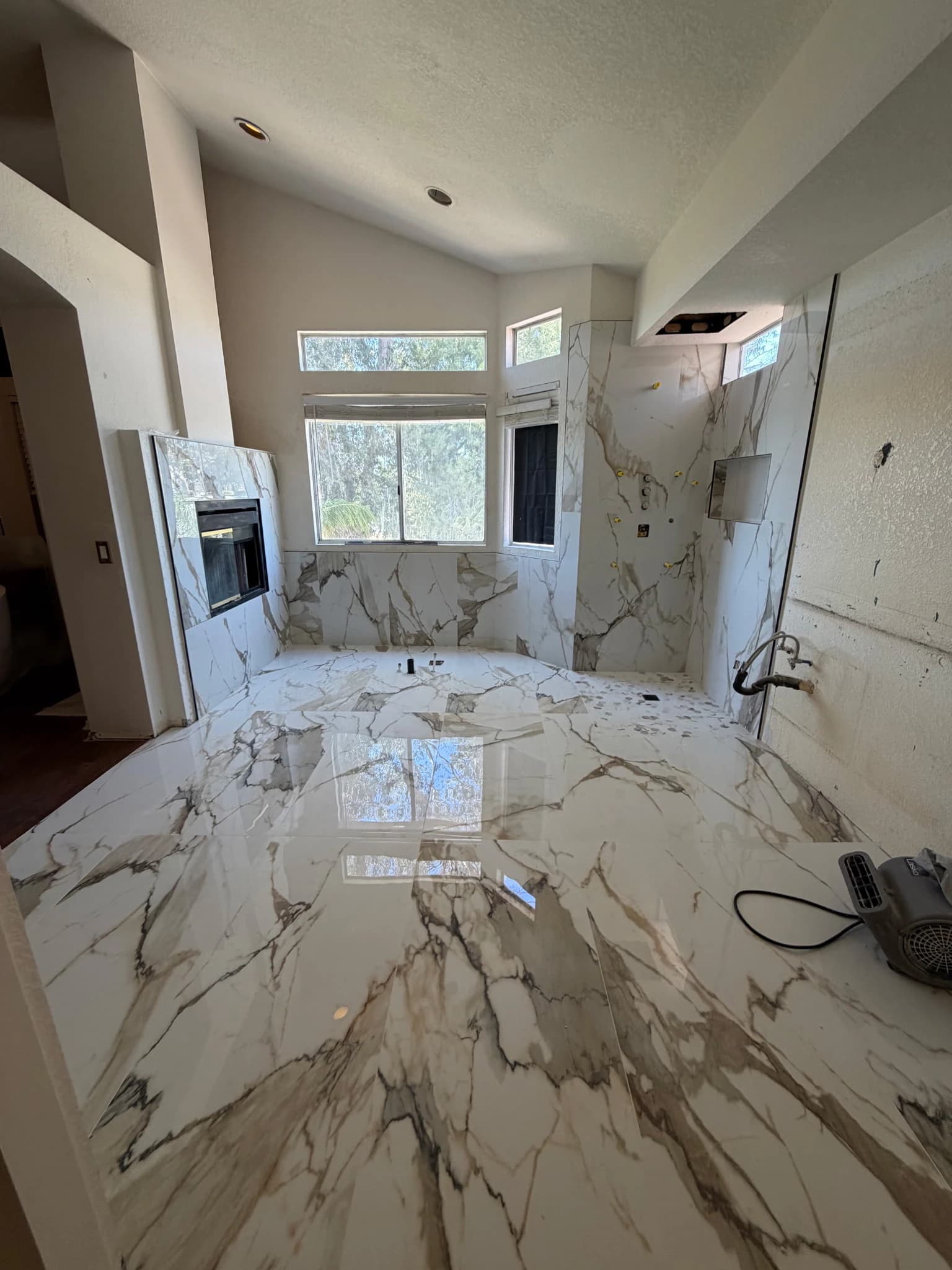Large-format marble-look tile installed across bathroom walls and floor during construction