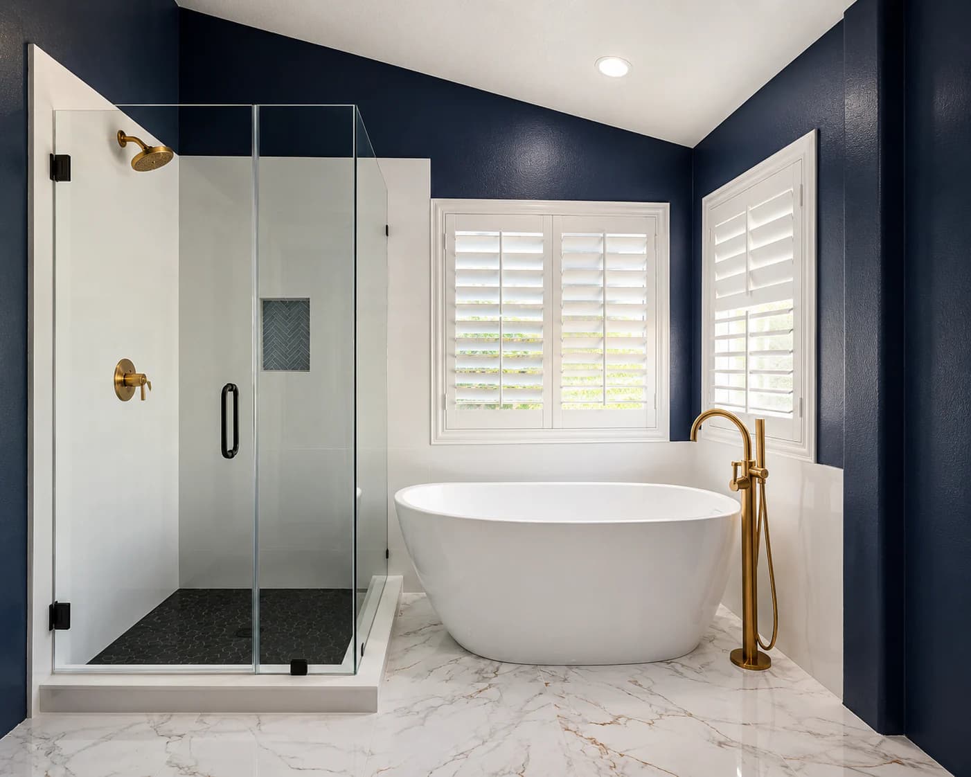Primary bathroom with a freestanding tub, glass shower, navy walls, and brass fixtures